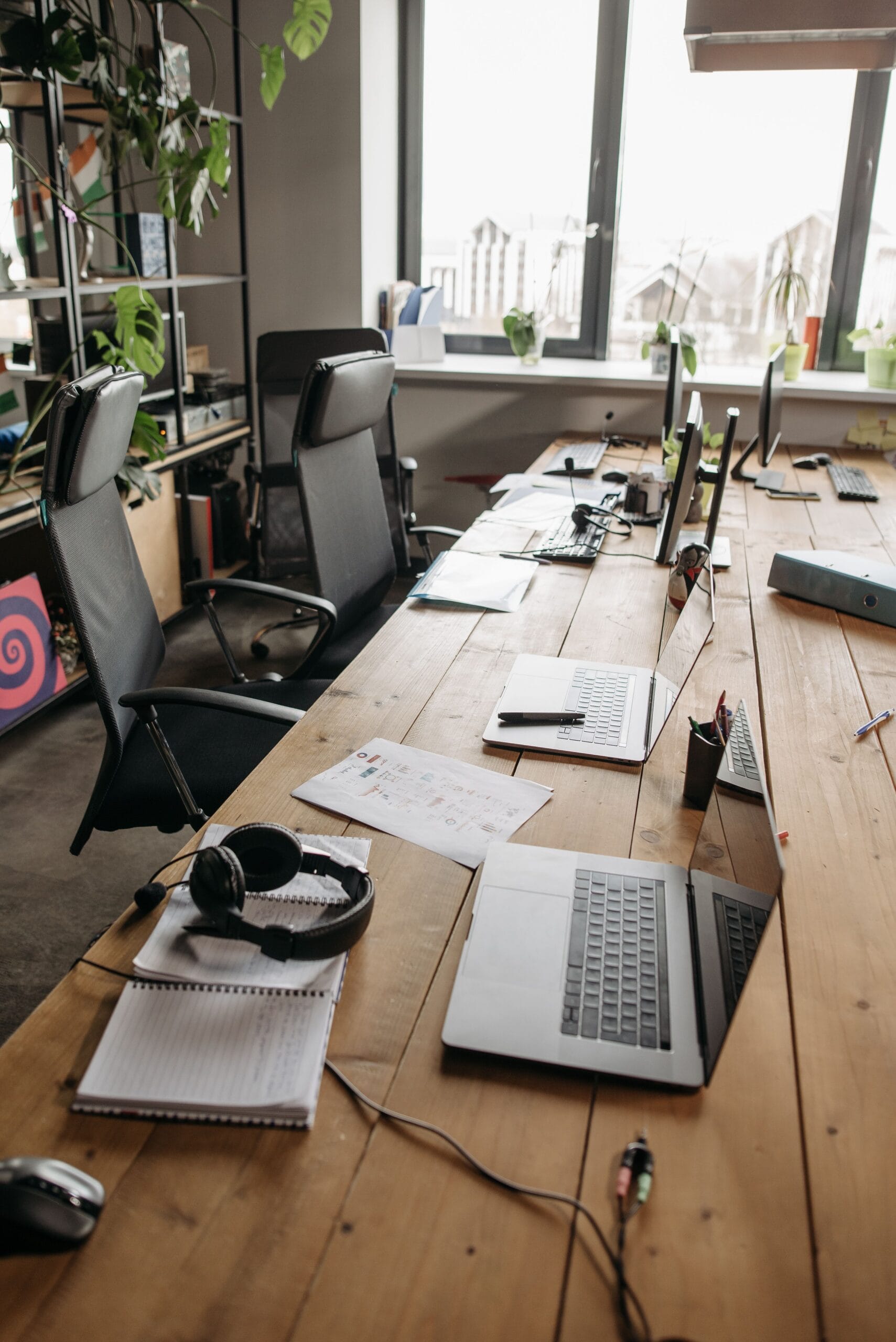 Laptops and chairs around a wooden table in a shared coworking space