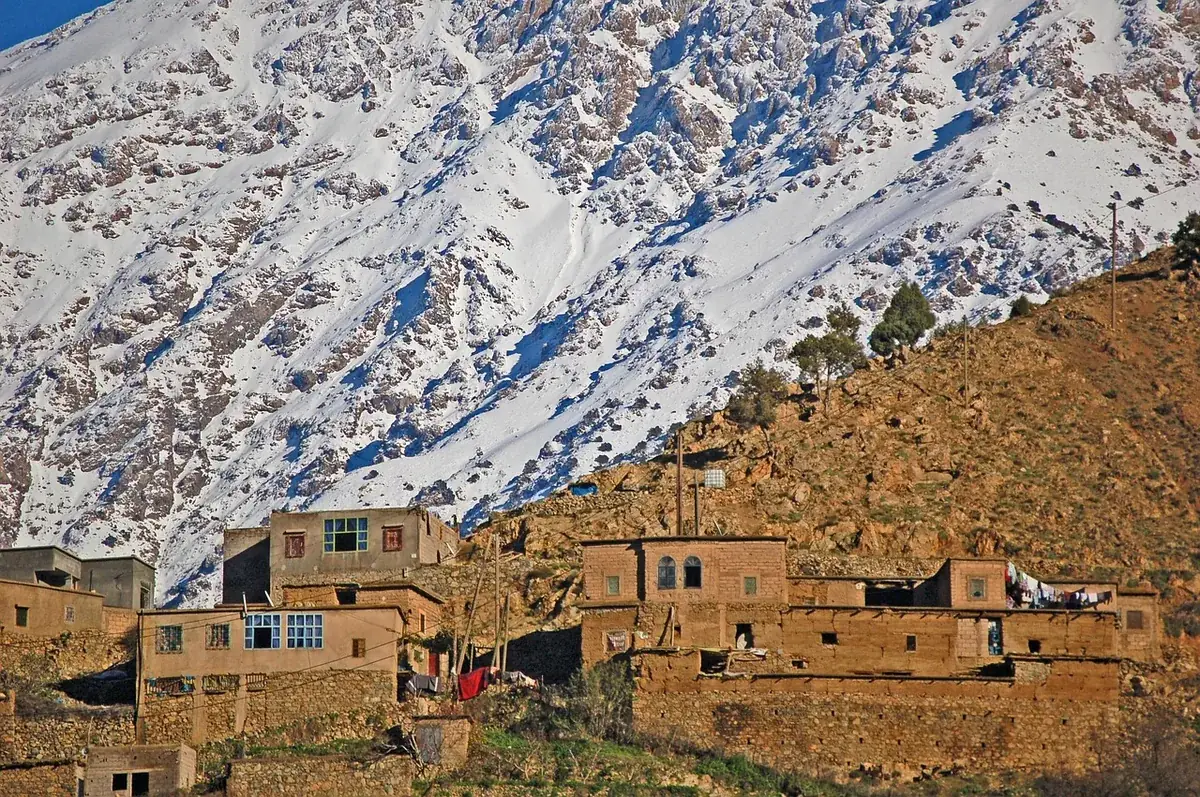A High Atlas village of mud-brick and stone beneath the snowline. This construction, unreinforced masonry on steep ground, is what the 2023 earthquake destroyed, and what the reconstruction is still working through