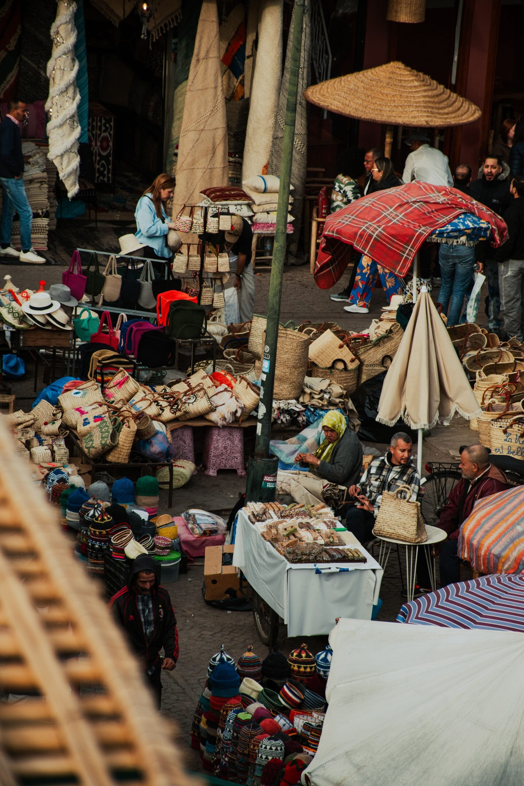 A Marrakech souk seen from above, stalls of baskets, hats and rugs with shoppers moving between them