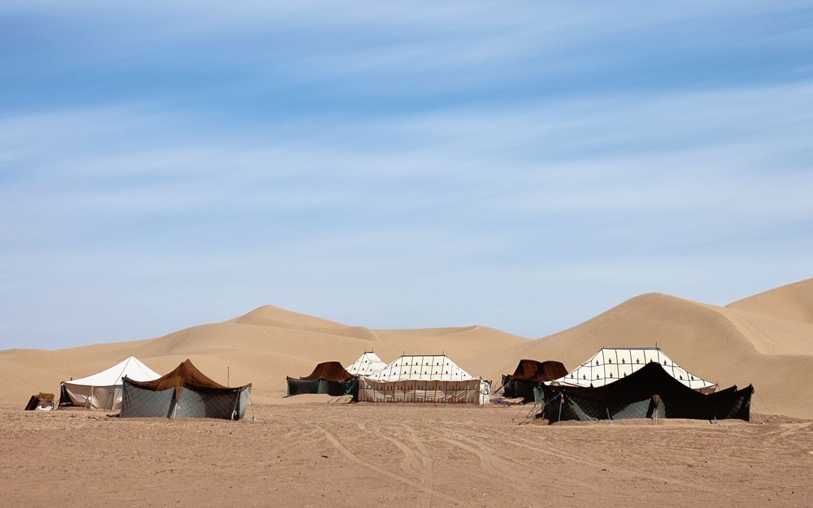 Tents pitched on flat sand near M Hamid El Ghizlane, with low dunes behind rather than a high erg