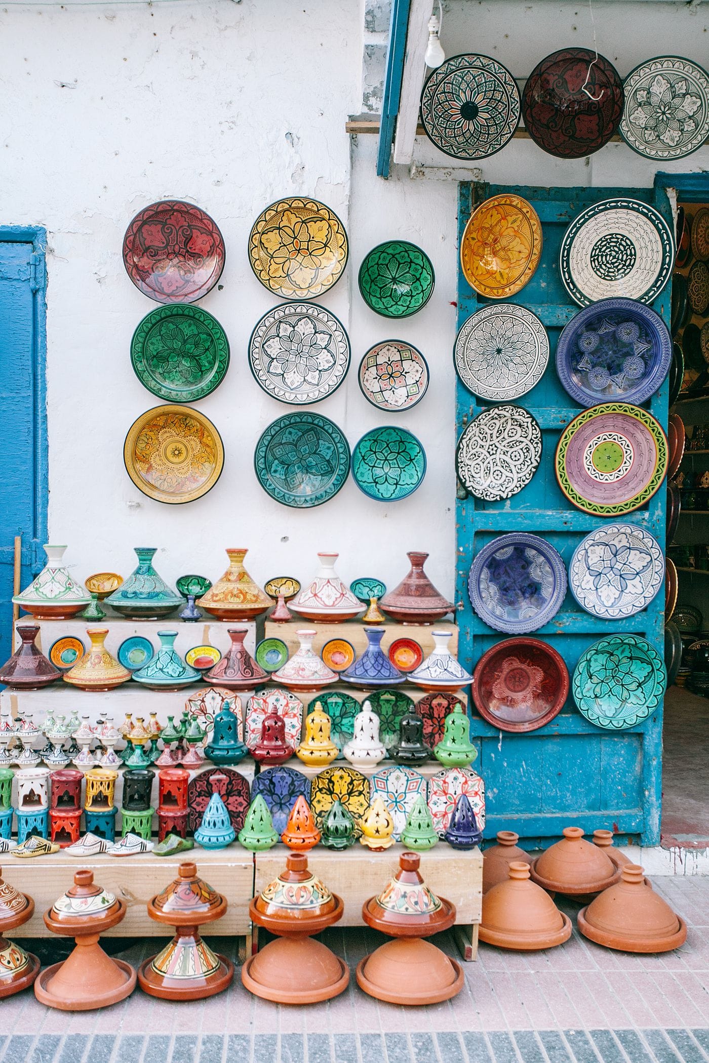 The exterior of a Moroccan souk shop displaying stacked metalware, lanterns and ceramics