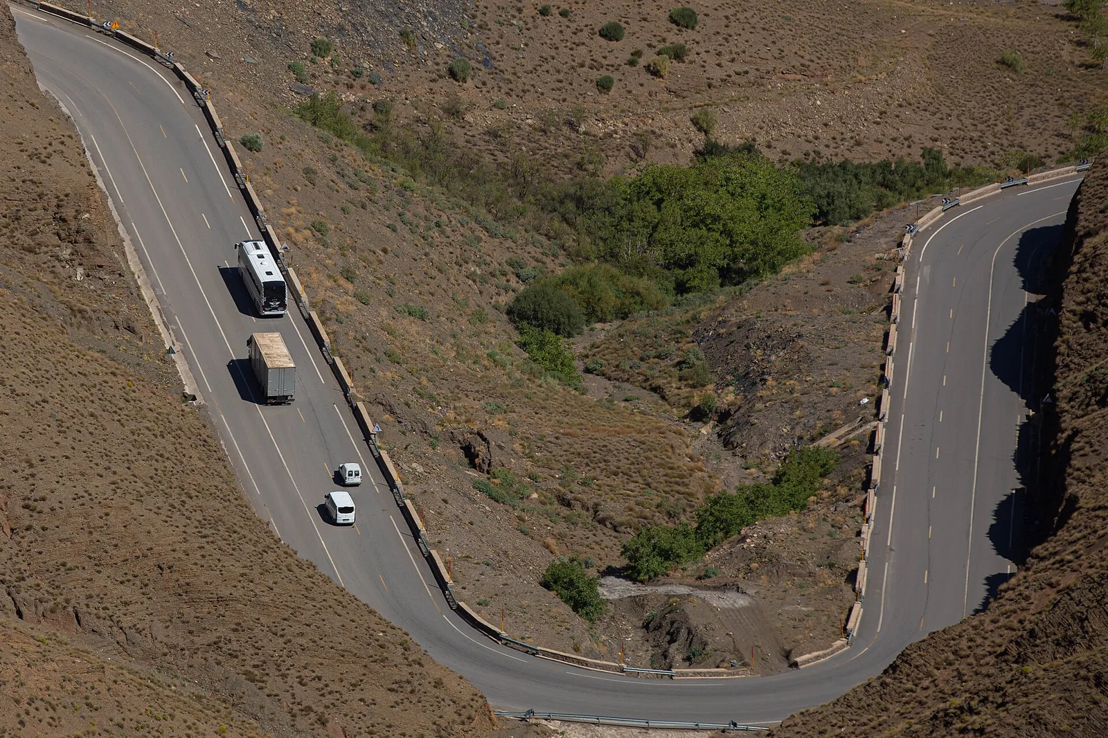 A coach, a lorry and two white tour minibuses on a hairpin of the Tizi n’Tichka road, the first leg of every Morocco desert tour from Marrakech